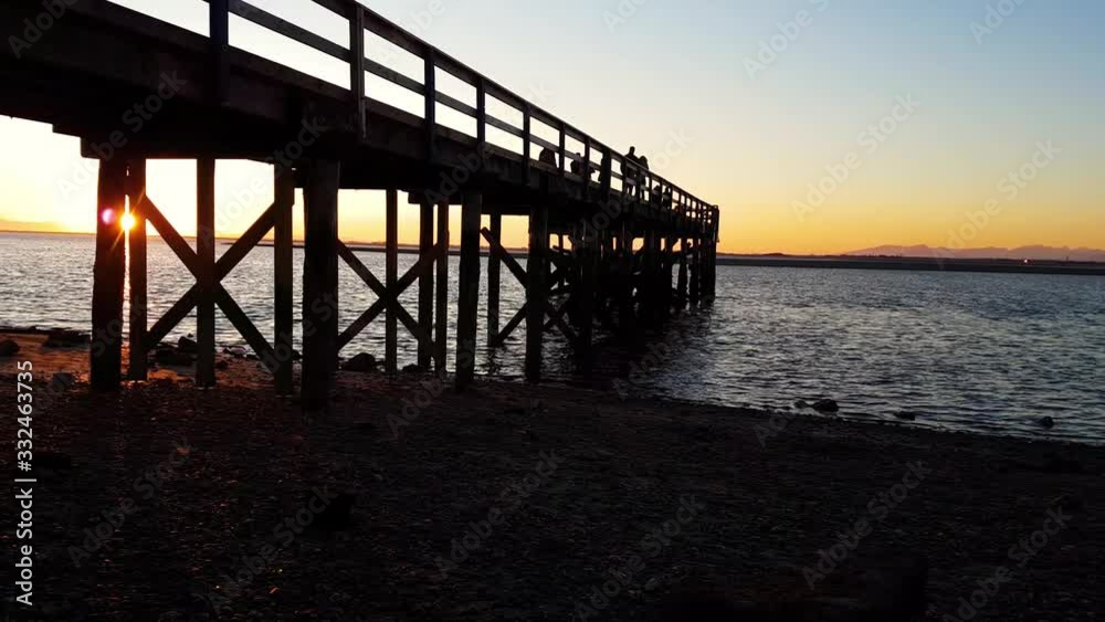 Beautiful Calm View of the Pacific Ocean on the shore near a wooden Quay during a vibrant and colorful winter sunset. Taken in Blackie Spit, White Rock, Vancouver, British Columbia, Canada. Beautiful Calm View of the Pacific Ocean on the shore near a wooden Quay during a vibrant and colorful winter sunset. Taken in Blackie Spit, White Rock, Vancouver, British Columbia, Canada.