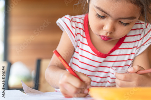 The girl is drawing and coloring with determination.