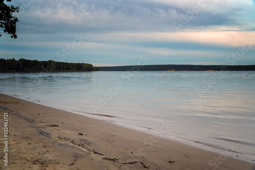 Fototapeta Naklejka Na Ścianę i Meble -  View of a large river with a sandy Bank against cloudy sky in the evening