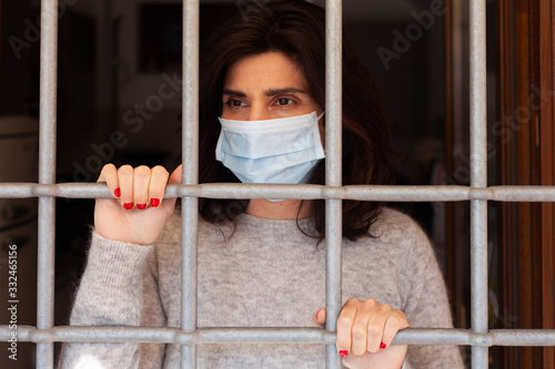 Coronavirus in Italia: una ragazza protetta dalla mascherina si affaccia dall'inferriata della sua finestra