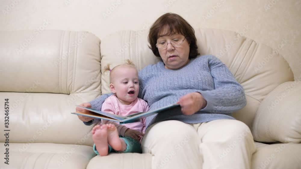 grandmother and granddaughter are sitting on the couch and are considering a children's book grandmother and granddaughter are sitting on the couch and are considering a children's book