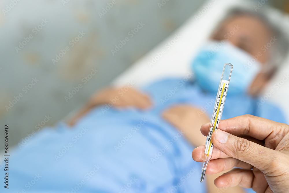 Doctor holding thermometer to measures asian senior or elderly old lady woman patient wearing a face mask have a fever in hospital : healthy strong medical concept.