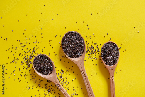 Chia seeds in wooden spoons. Superfood on a yellow background