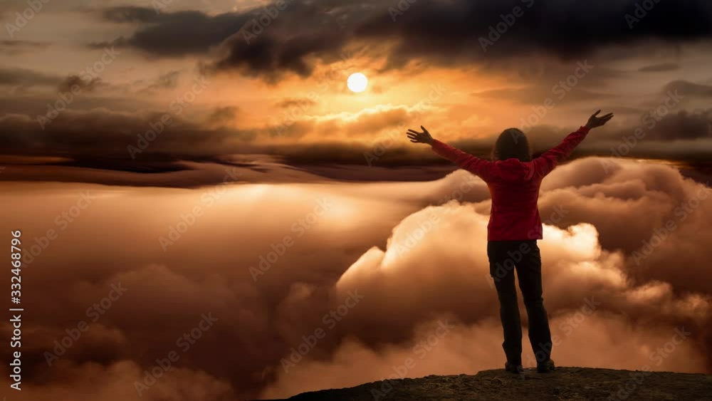 Girl on a Rocky Mountain Peak with Beautiful and striking view of the puffy clouds during a colorful and vibrant sunset or sunrise. Nature Background. Still Image Continuous Animation Cinemagraph Girl on a Rocky Mountain Peak with Beautiful and striking view of the puffy clouds during a colorful and vibrant sunset or sunrise. Nature Background. Still Image Continuous Animation Cinemagraph