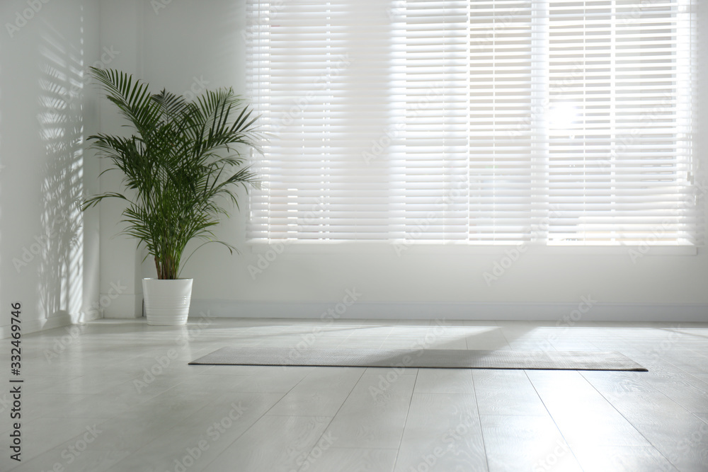 Unrolled grey yoga mat on floor in room. Space for text Unrolled grey yoga mat on floor in room. Space for text