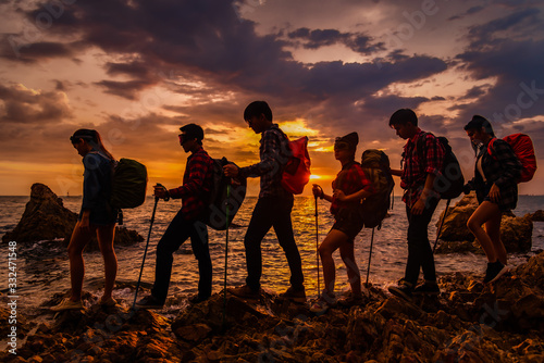 Group of asian hikers friends team with backpacks walking and adventure doing climbing