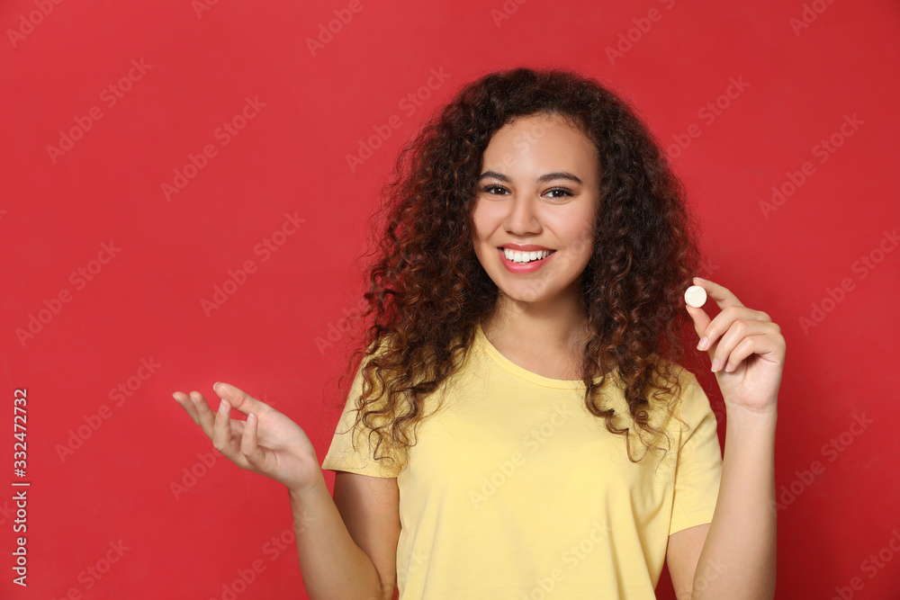 African-American woman with vitamin pill on red background African-American woman with vitamin pill on red background