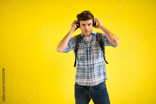 young man with backpack and headphones on yellow