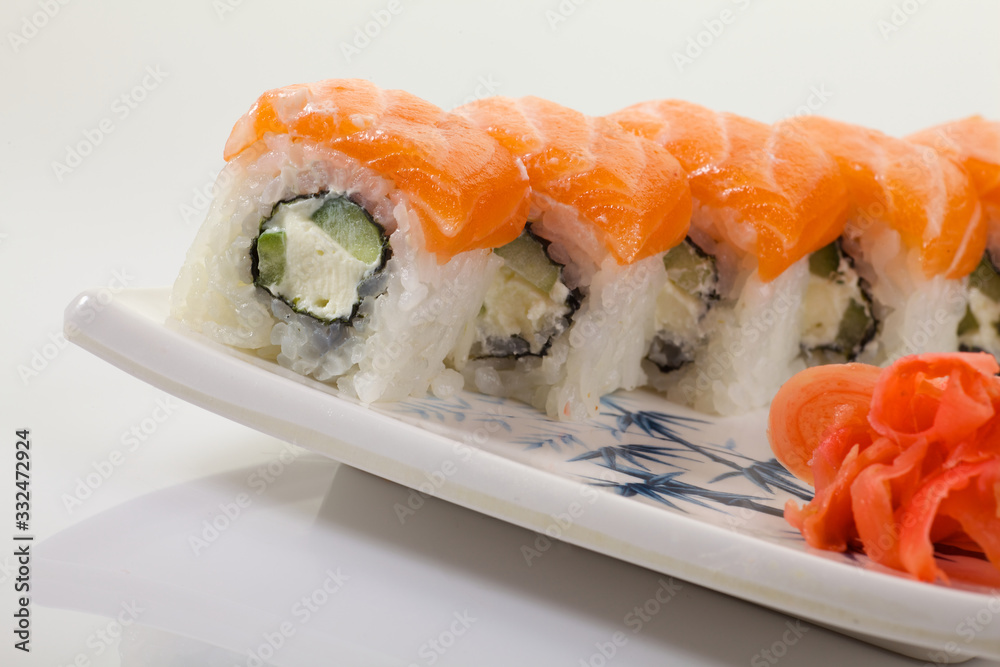 Japanese Cuisine - Appetizing Salmon Sushi Set. Philadelphia Sushi Roll - Maki Sushi with Philadelphia Cheese inside on mirror black background. Smoked salmon rolls served on a plate