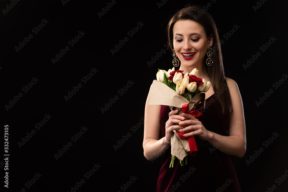 excited woman in dress looking at bouquet isolated on black excited woman in dress looking at bouquet isolated on black