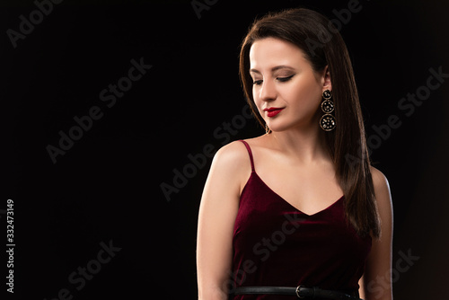 attractive woman in dress looking down isolated on black
