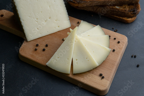 Queso curado Manchego español sobre una tabla de cortar