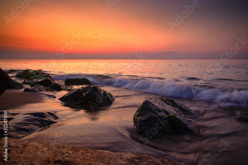 Sunrise at sea. Stones  waves and the sun. Seascape.
