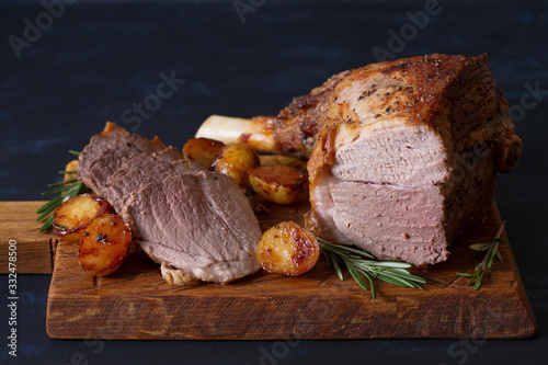Roast leg of lamb with potatoes and rosemary on dark background. horizontal image photo