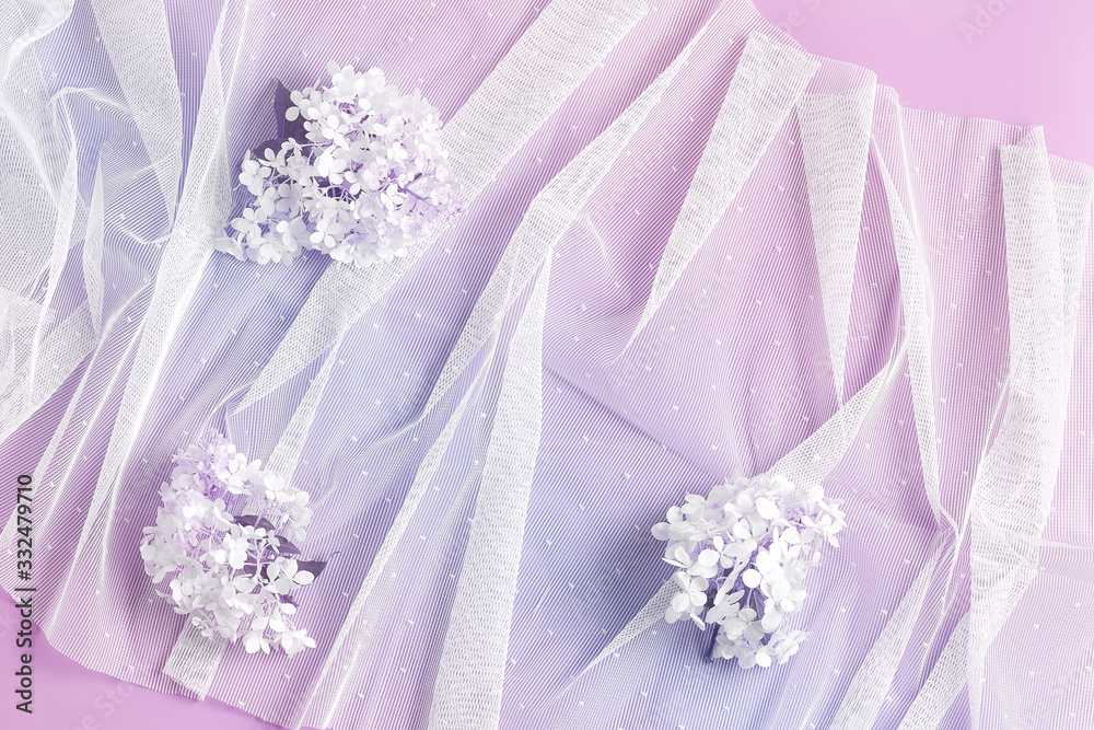 large hydrangea flowers on white tulle. pink background. wedding floral concept. flat lay, top view
