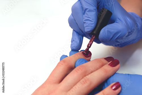manicure specialist covers the nails with red varnish, toned.