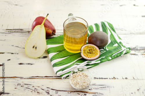 Still life with tea, pear, oats and passion fruit. Top view. On a beautiful vintage table with a modern print towel.