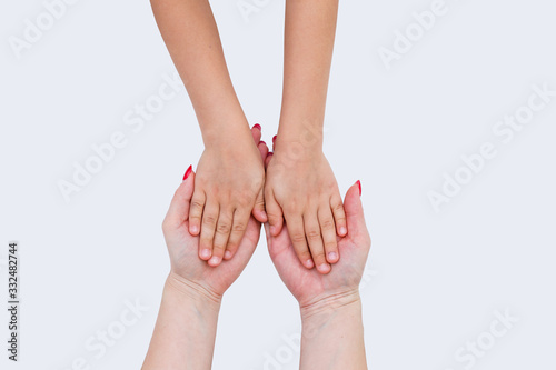 Hands of a baby next to mother's hands, closeup. In the open palm of the mother, two baby hands