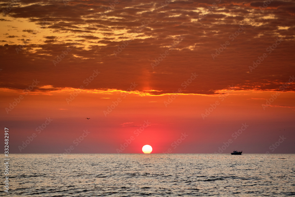  The boat is floating against the backdrop of the rising sun. Seascape. Black Sea
