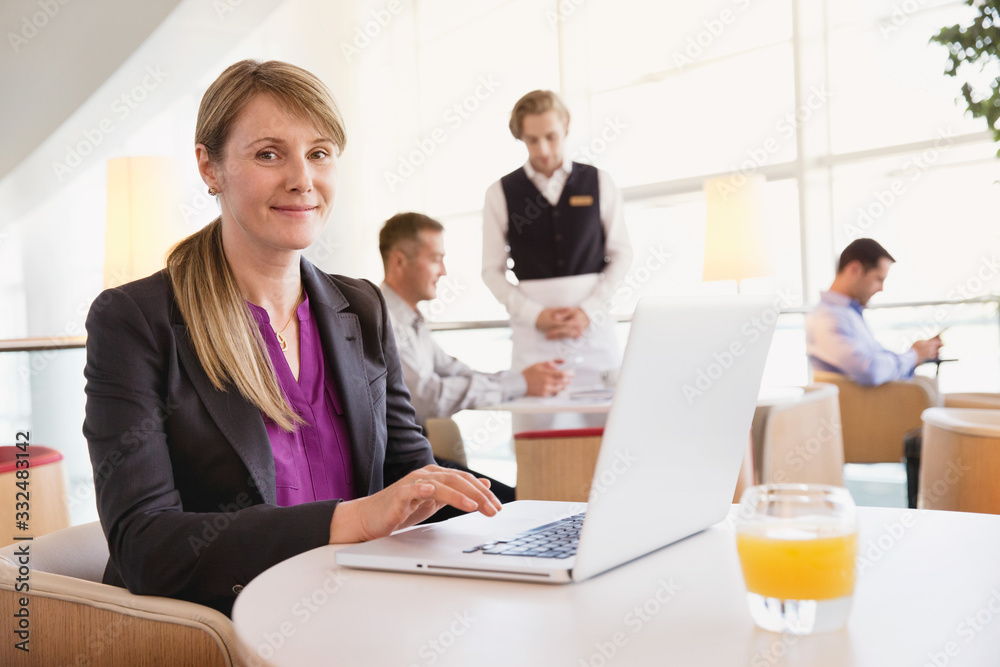 Portrait of businesswoman using laptop while people in background. Portrait of businesswoman using laptop while people in background.