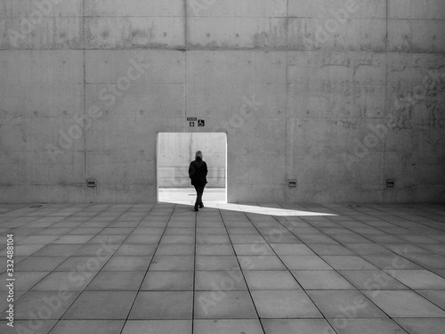 Schilderij op canvas Mujer pasando por una puerta abierta en un muro de hormigón en un lugar solitari