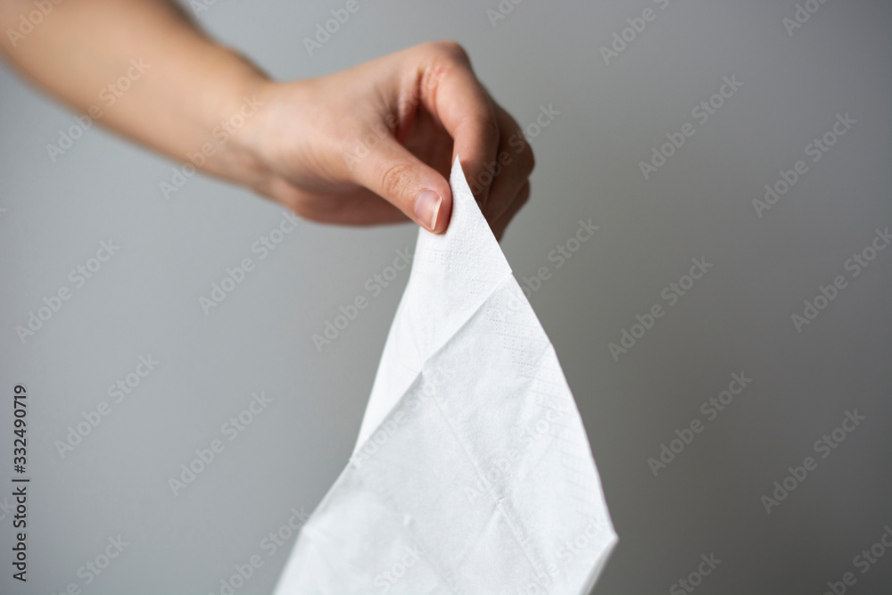 A female hand holding a white clean tissue paper. Coronavirus advice includes use a disposable paper tissue. A female hand holding a white clean tissue paper. Coronavirus advice includes use a disposable paper tissue.