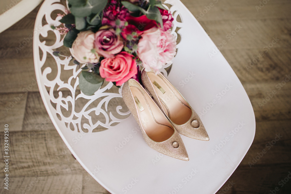 Elegant wedding shoes with rings and flowers on a white chair Elegant wedding shoes with rings and flowers on a white chair