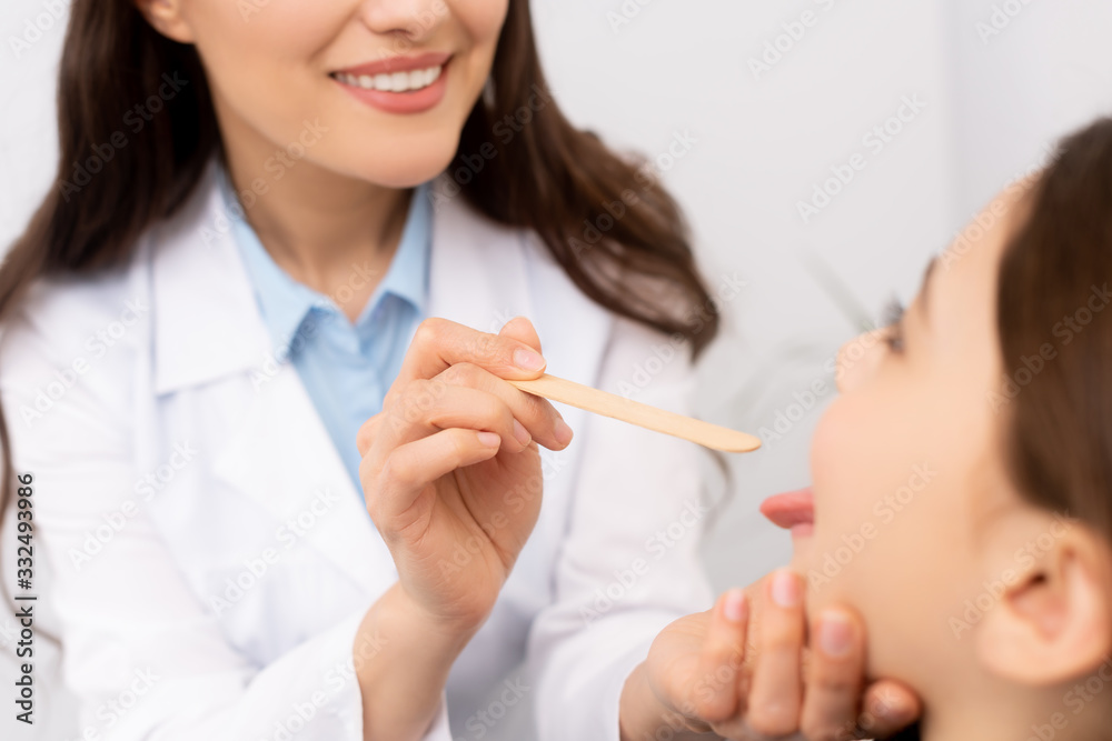 cropped view of ent physician examining throat of kid with tongue depressor cropped view of ent physician examining throat of kid with tongue depressor