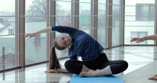 girls practice yoga in a large, light room. coach and student. sport training concept.