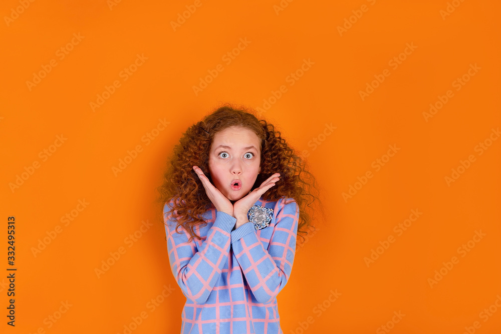 red haired and curly haired girl on an orange background, surprised red haired and curly haired girl on an orange background, surprised