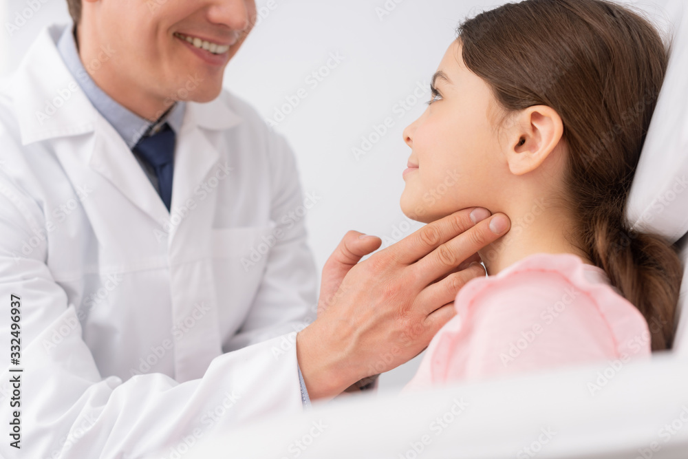 cropped view of smiling ent physician touching neck of cute child while examining her throat cropped view of smiling ent physician touching neck of cute child while examining her throat