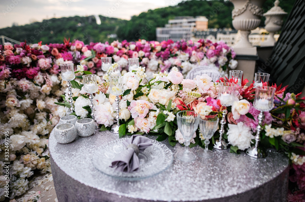 Table decorated for date for two, there are tableware, glasses, flowers, candles and tablecloth with napkins, the table is on a balcony
