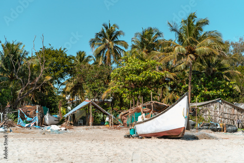 Fishing boat on the beach against the background of palm trees © Александр Беляшов