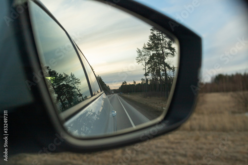 Reflection of the highway in a car mirror. Toned photo. Road travel concept.Driving car in sunset.Beauty on sky going on trip at night.reflection of the road in the sunset sunlight blurry