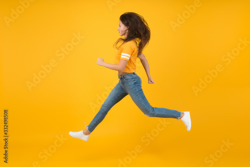 Feel inner energy. Pretty girl with long hair. Fashion style. Beauty and make up. Energetic woman running or jumping. Skinny jeans suits her. Sexy girl yellow background. Sensual girl in casual style
