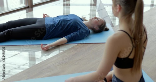 girls practice yoga in a large, light room. coach and student. sport training concept.