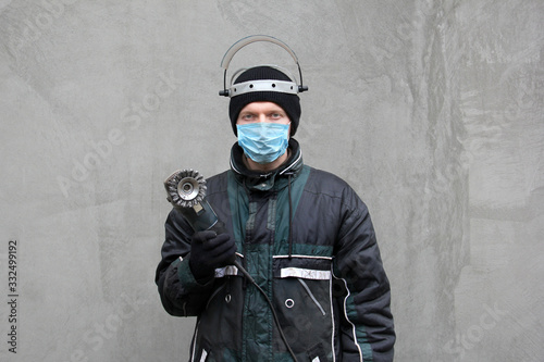 Fototapeta Naklejka Na Ścianę i Meble -  Masked man with grinder in hands