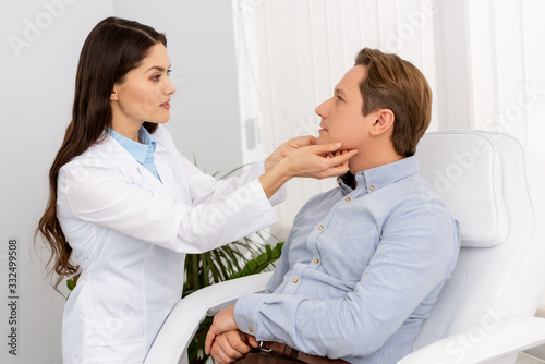 beautiful, attentive ent physician examining handsome patient in clinic