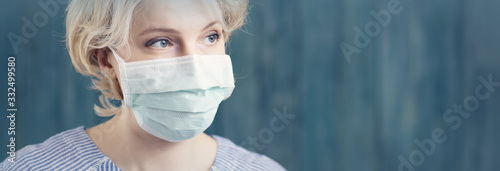 young woman in medical face protection mask indoors on blue background