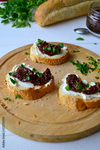 French baguette with cream cheese and dried tomatoes on a white background.