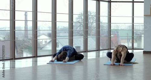 girls practice yoga in a large, light room. coach and student. sport training concept.