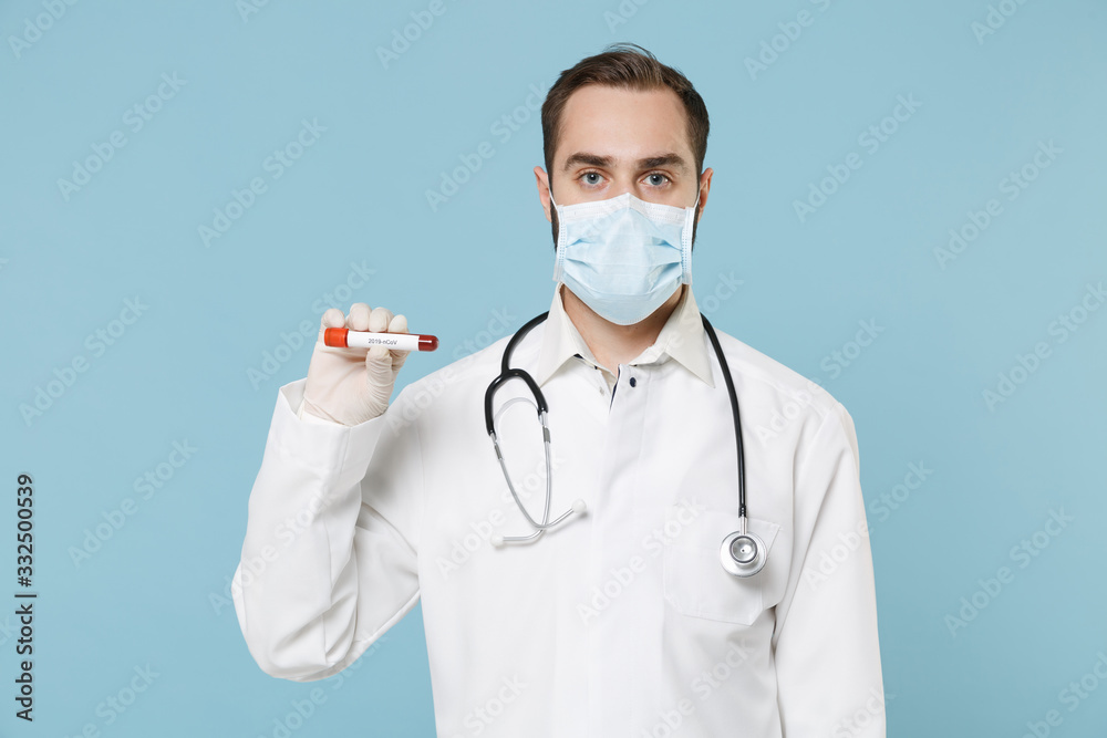 Male doctor man in medical gown sterile face mask gloves isolated on blue wall background. Epidemic pandemic coronavirus 2019-ncov sars covid-19 flu virus concept. Hold blood test result Sample tube.