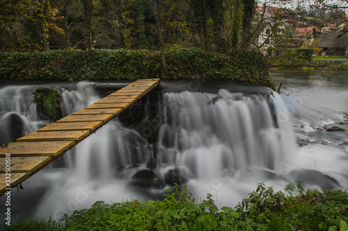 Man made cascades on the river of Krka close to Zuzemberk in slovenia  used to power an old wood sawmill. Visible wooden bridge over the water.