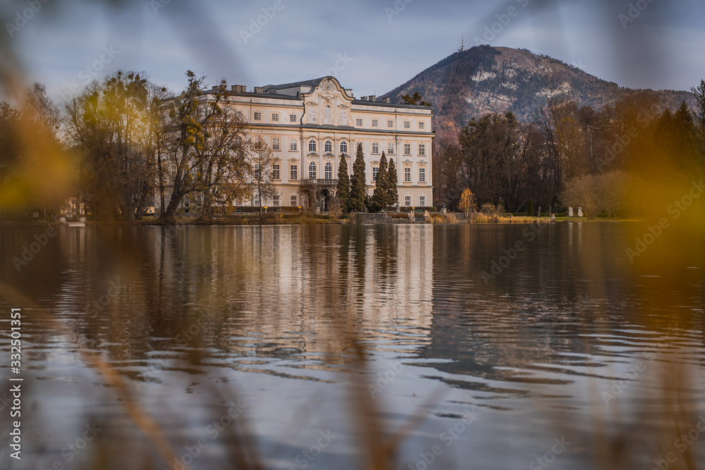 Cold autumn panorama of Schloss Leopoldskron and the Leopoldskroner Weiher in Salzburg, Austria. Beautiful hotel where the sound of music was filmed rising just out of the water.