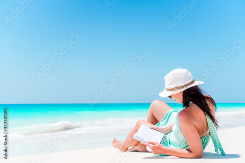 Young woman reading book during tropical white beach