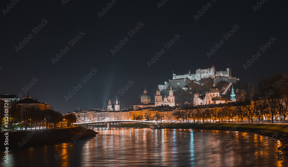 Night panorama or nightscape of the city of salzburg on a cold autumn evening, looking from the bridge above the river towards downtown.