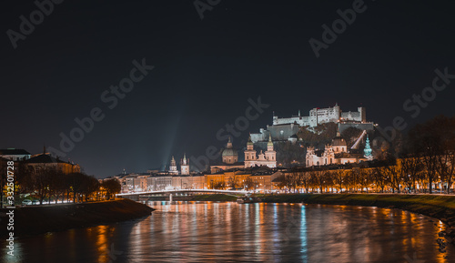 Night panorama or nightscape of the city of salzburg on a cold autumn evening  looking from the bridge above the river towards downtown.