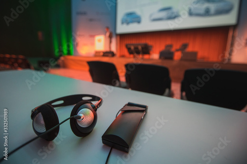 Wireless headphones and the reciever used for simultaneous translation on multilingual conferences or events seen resting on a table during lecture. photo