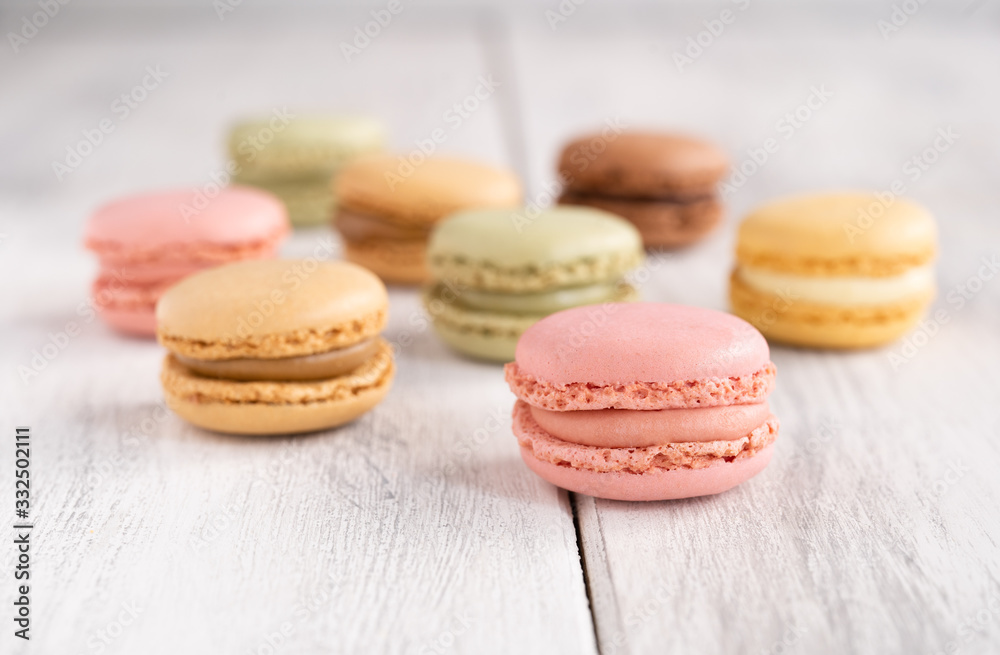 Colorful tasty macaroons stacked in pile against wooden white surface Colorful tasty macaroons stacked in pile against wooden white surface