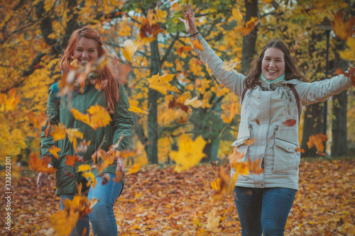 Photography Two women throwing autumn leaves in the air in romantic forest